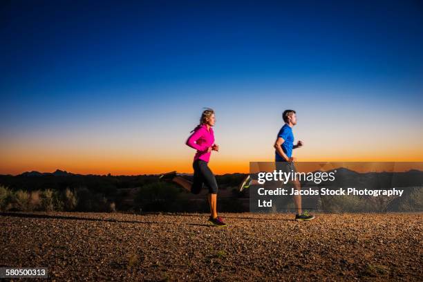 caucasian couple running on remote road - white gravel stock pictures, royalty-free photos & images