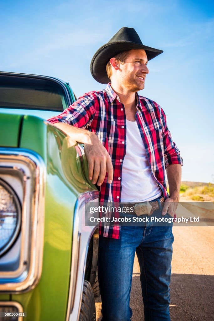 Caucasian man leaning on truck on rural road