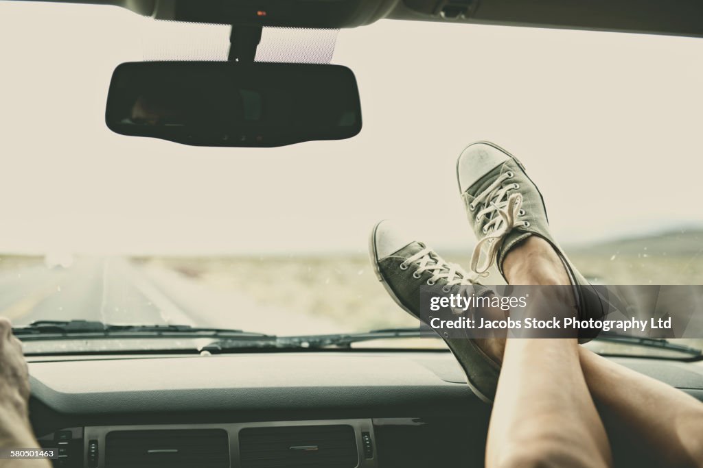 Caucasian couple riding in car with feet on dashboard