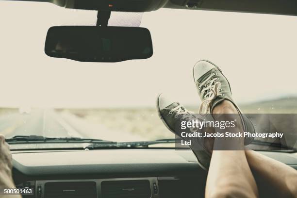 caucasian couple riding in car with feet on dashboard - car dashboard fotografías e imágenes de stock