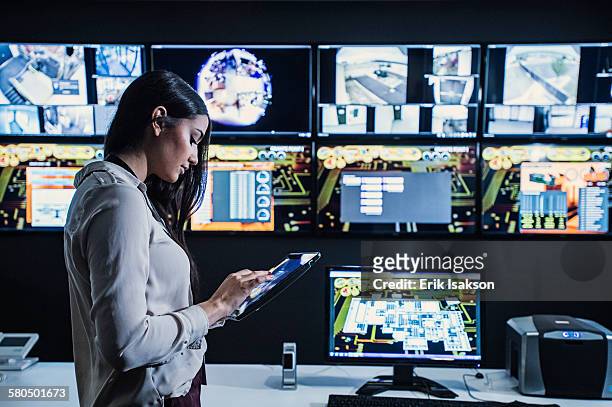 hispanic security guard using digital tablet in control room - sala de controle - fotografias e filmes do acervo