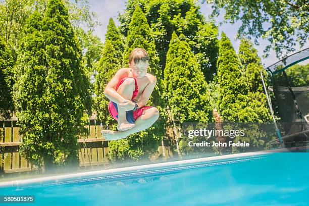 caucasian boy jumping into swimming pool - cannonball diving stock-fotos und bilder