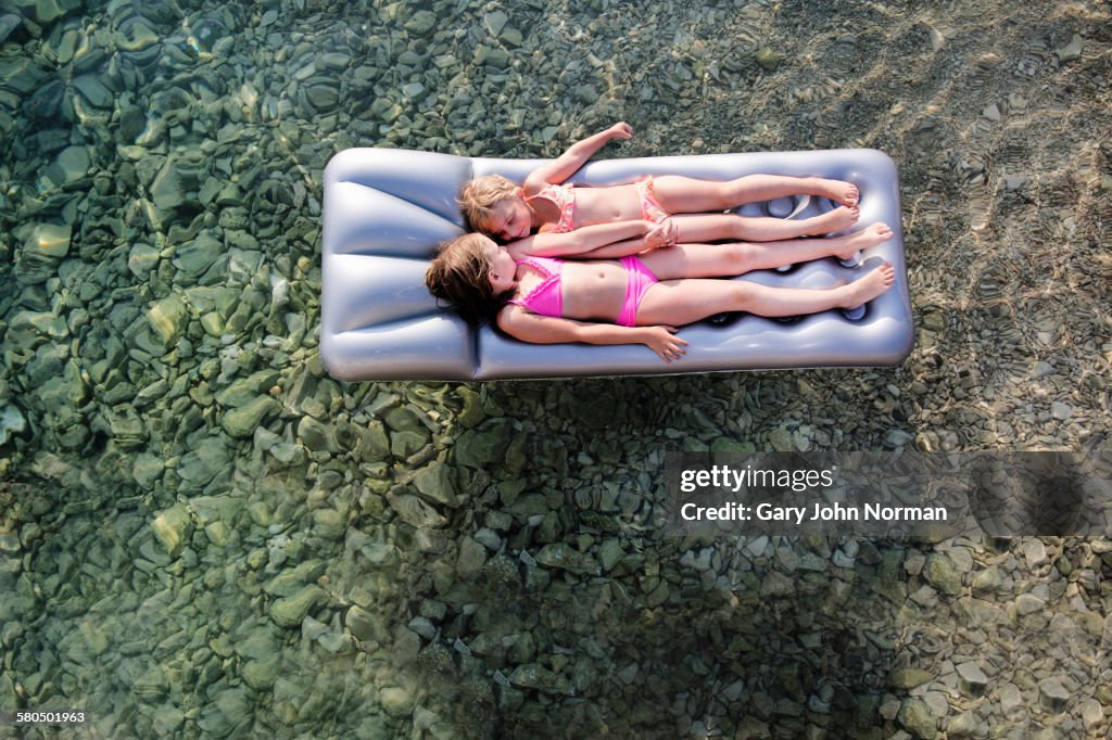 Caucasian girls floating on raft in lake