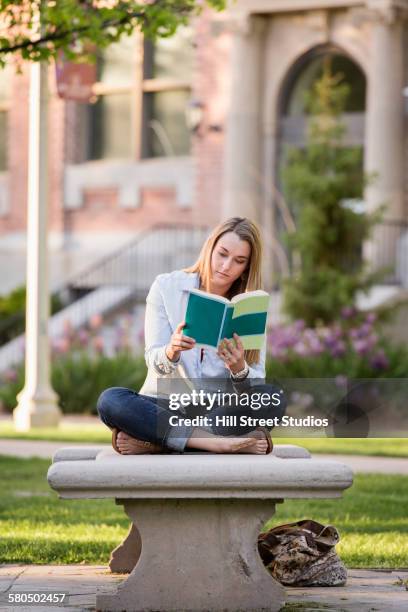 student reading book on college campus - mujer leyendo libro en el parque fotografías e imágenes de stock