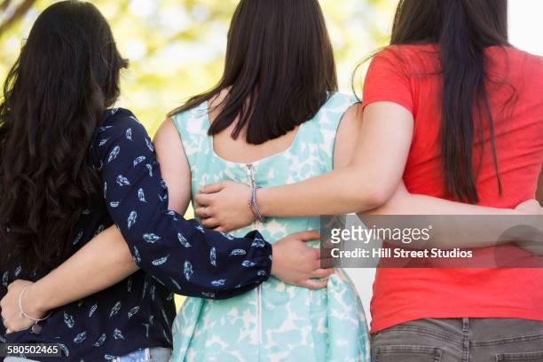 rear view of students hugging on college campus - arm in arm stock pictures, royalty-free photos & images