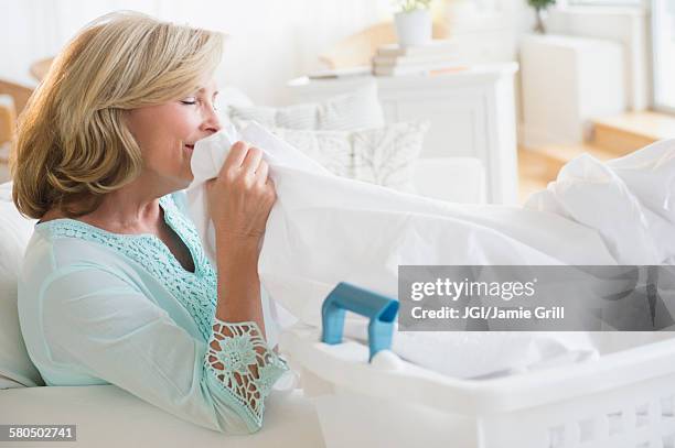 caucasian woman smelling clean laundry - white laundry foto e immagini stock