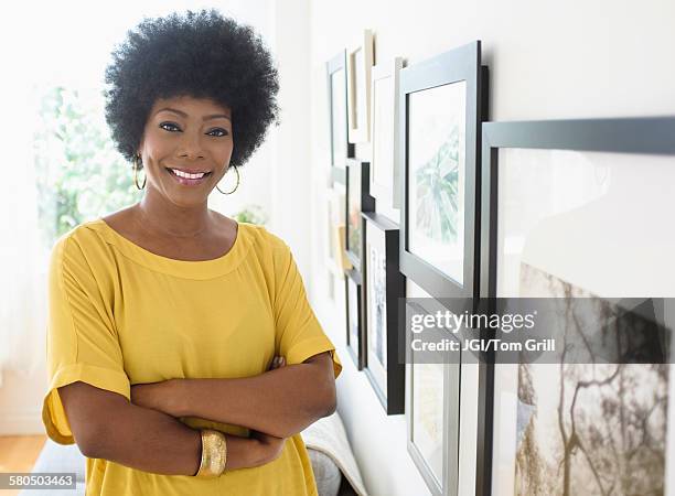 african american woman standing near pictures on wall - wall hanging stock pictures, royalty-free photos & images