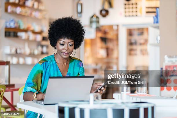 african american business owner using laptop in store - propietario fotografías e imágenes de stock