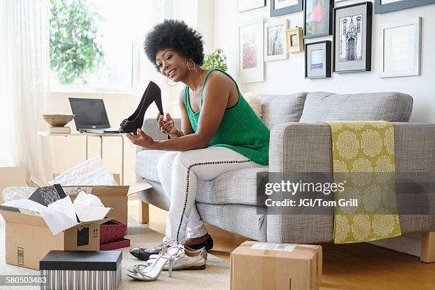 african american woman opening packages of shoes on sofa - calzature nere foto e immagini stock