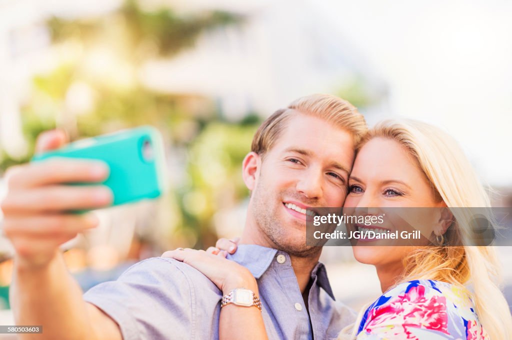 Caucasian couple taking selfie on cell phone