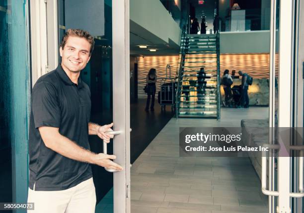 hispanic bellboy opening hotel door - doors of the 21st century ストックフォトと画像