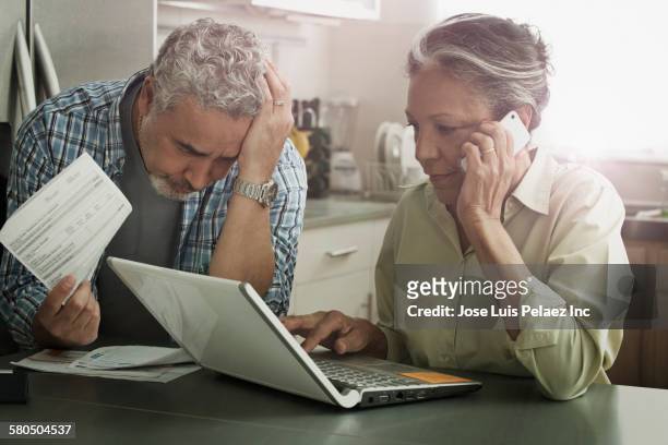 stressed hispanic couple paying bills on laptop - bills payment stock-fotos und bilder
