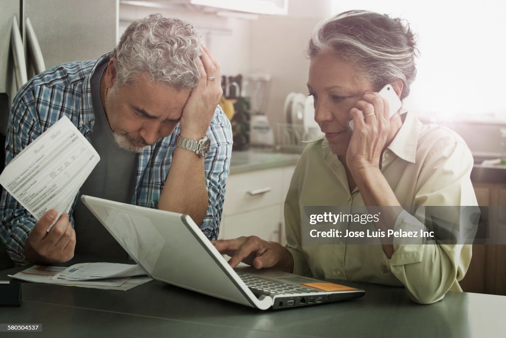 Stressed Hispanic couple paying bills on laptop