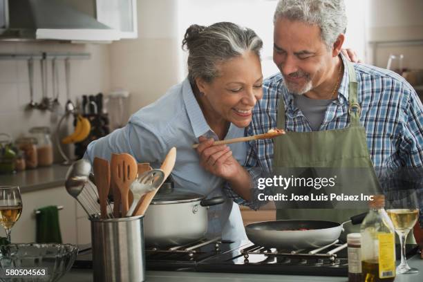 hispanic couple cooking in kitchen - person cooking pan stock pictures, royalty-free photos & images