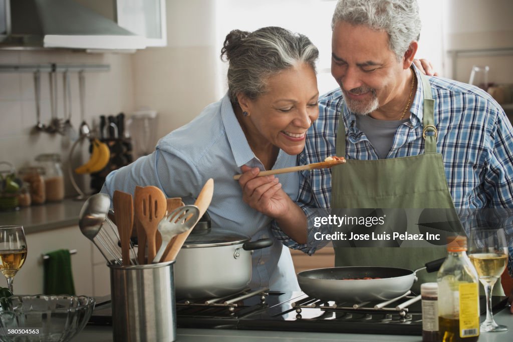 Hispanic couple cooking in kitchen