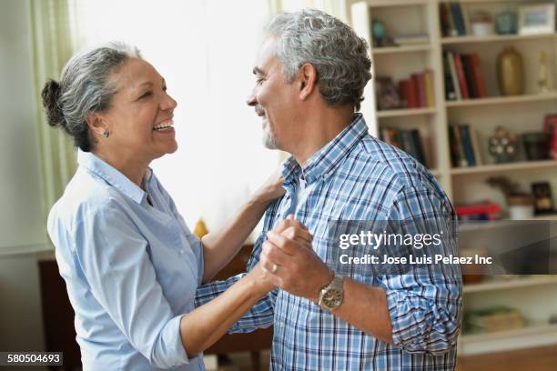hispanic couple dancing in living room - couple dancing at home stockfoto's en -beelden