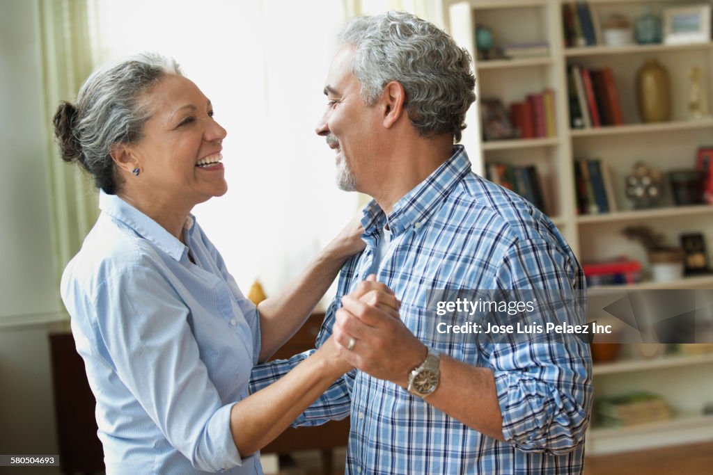 Hispanic couple dancing in living room