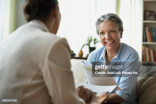 hispanic saleswoman talking to client in living room - lebensversicherung stock-fotos und bilder