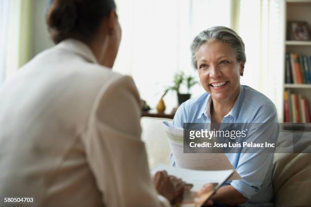 hispanic saleswoman talking to client in living room - life insurance stock pictures, royalty-free photos & images