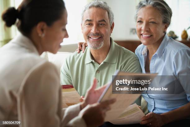 hispanic saleswoman talking to clients in living room - lebensversicherung stock-fotos und bilder