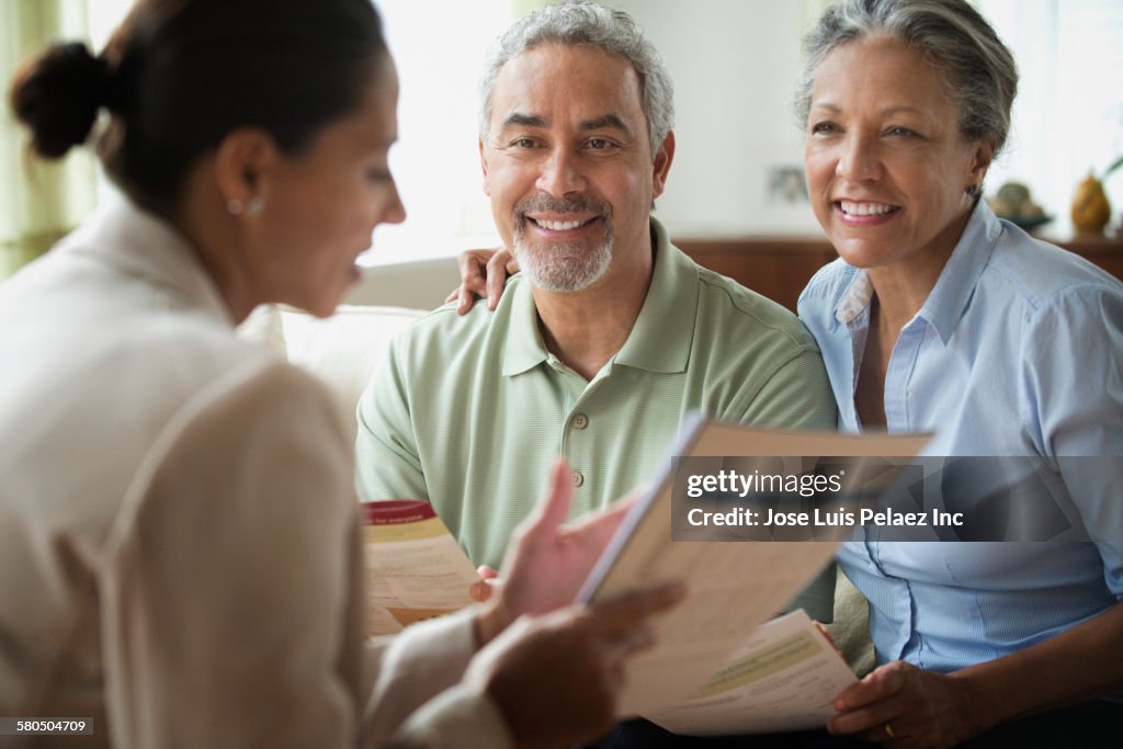 Hispanic saleswoman talking to clients in living room