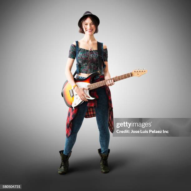 smiling caucasian woman playing guitar - woman holding guitar fotografías e imágenes de stock