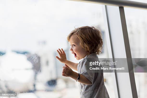 caucasian baby boy looking out airport window - toddler at airport stock-fotos und bilder