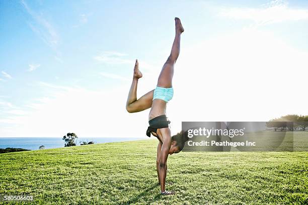 african american woman practicing yoga in park - fare la verticale sulle mani foto e immagini stock