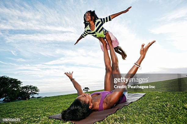 mother balancing daughter on legs in park - acroyoga stock pictures, royalty-free photos & images