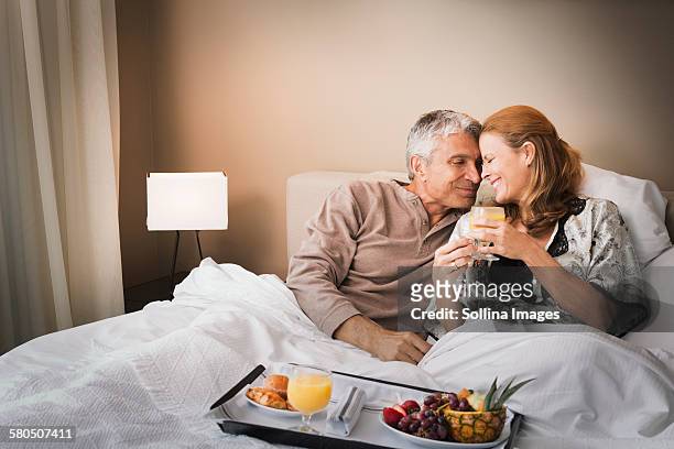 smiling couple having breakfast in bed - couple breakfast stock-fotos und bilder