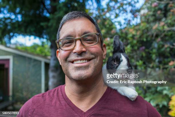 Mixed race man carrying rabbit on shoulder