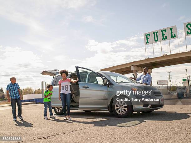 family around their minivan at a gas station - minivan ストックフォトと画像