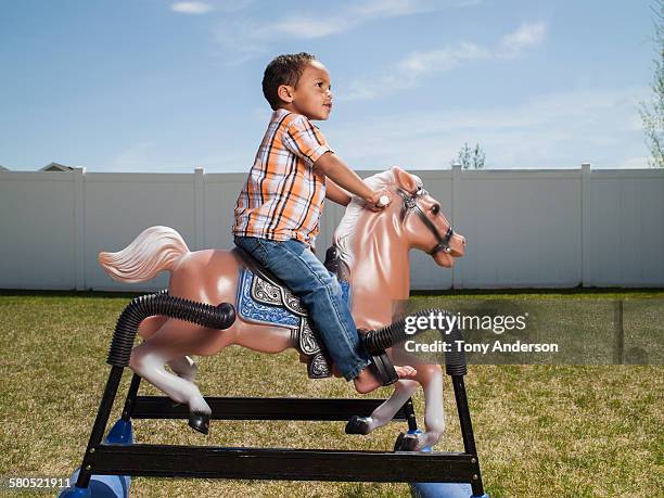 boy riding hobby horse toy in back yard - hobby horse stock pictures, royalty-free photos & images