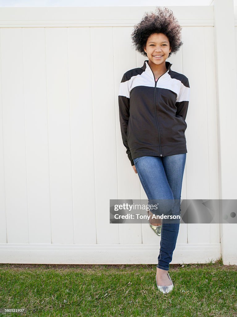 Teenaged girl leaning on fence in back yard