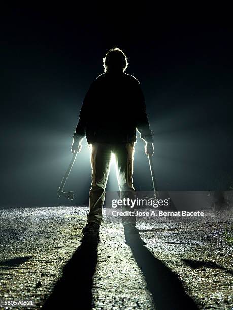 road with a silhouette of a man with an ax - murderer - fotografias e filmes do acervo