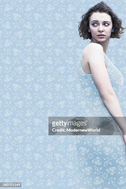 a female dressed same pattern with the wall paper - same person different clothes stock-fotos und bilder