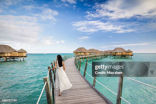 guest walking on the footbridge to water bungalows - tahiti stock pictures, royalty-free photos & images