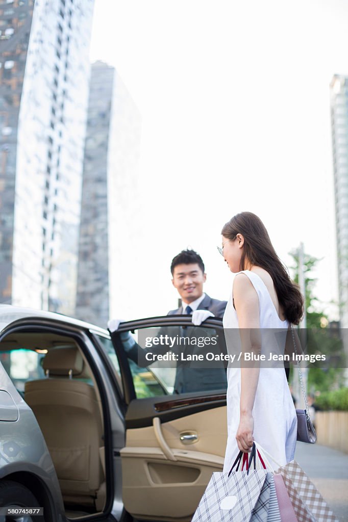 Chauffeur opening car door for a young woman