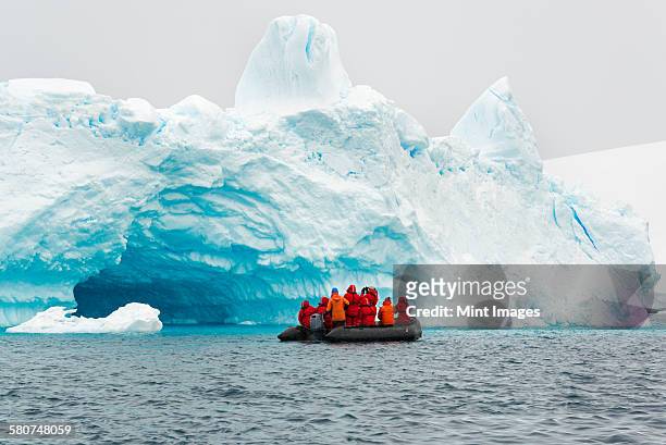 group of people crossing the ocean in the antarctic in a rubber boat, icebergs in the background. - explore stockfoto's en -beelden