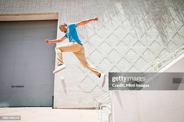 young man, a parcour runner jumping in the air down a stairway. - parcours stadt stock-fotos und bilder