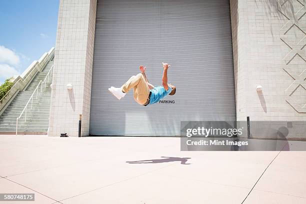 young man somersaulting, a parcour runner on the street - backflipping fotografías e imágenes de stock