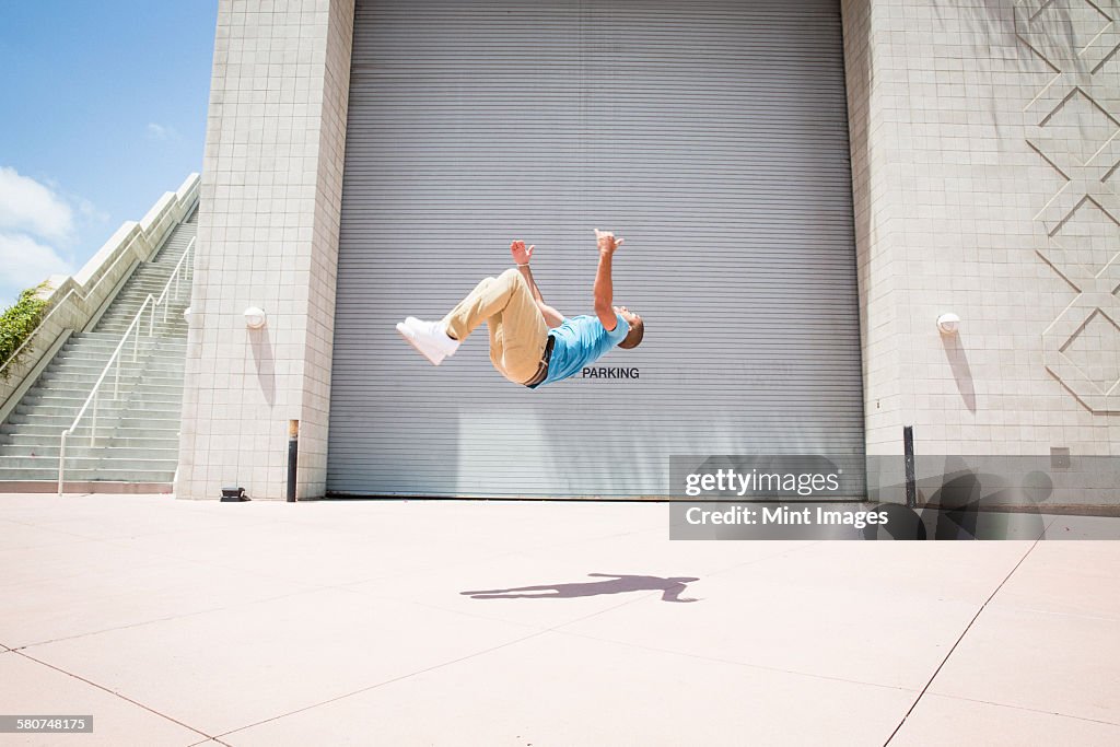 Young man somersaulting, a parcour runner on the street