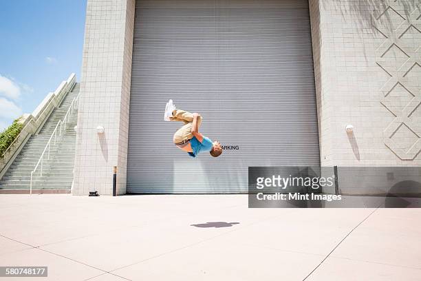 young man somersaulting, a parcour runner on the street - backflipping imagens e fotografias de stock