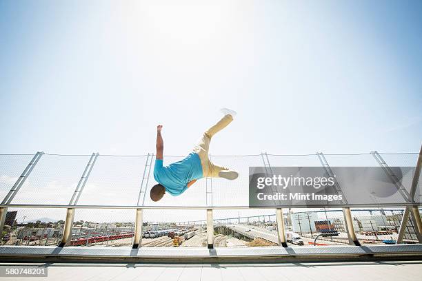 young man somersaulting on a bridge. - back flip bridge stock pictures, royalty-free photos & images