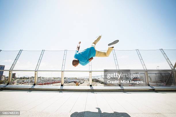 young man somersaulting on a bridge. - back flip bridge stock pictures, royalty-free photos & images