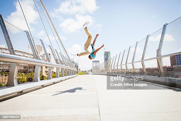 young man somersaulting on a bridge. - acrobatic activity fotografías e imágenes de stock