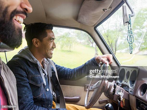 two young men in a car, driver and passenger, smiling. - front passenger seat stock-fotos und bilder