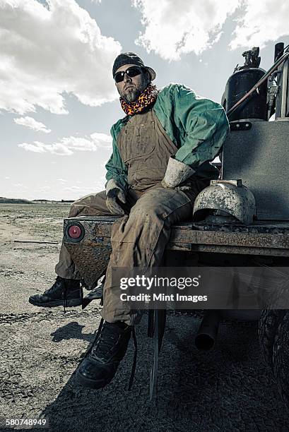 a welder seated on a truck with his gear beside him. - welding mask stock pictures, royalty-free photos & images