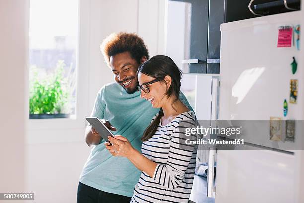 happy young couple having fun in their kitchen - happy couple at home stockfoto's en -beelden