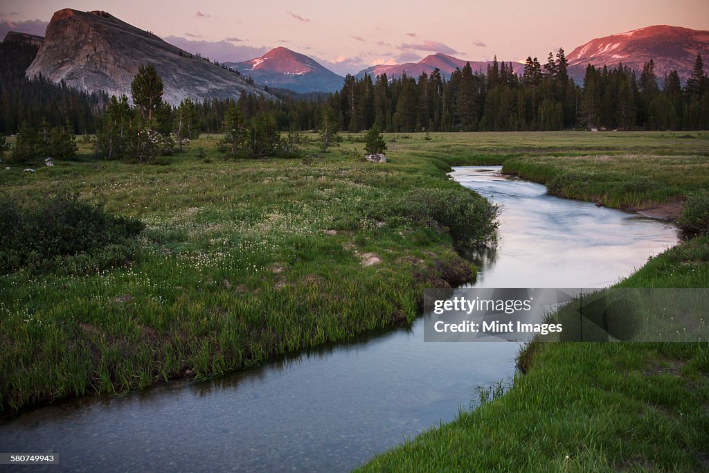 View of a river running through grassland in a valley in California.